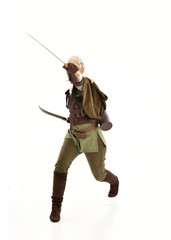 Obraz premium full length portrait of a blonde girl wearing green and brown medieval costume, holding a bow and arrow. isolated on white background.