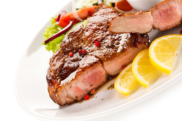 Roast steak with vegetables on white background