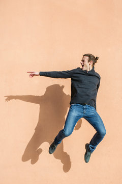 Teenage boy jumping in front of a wall.