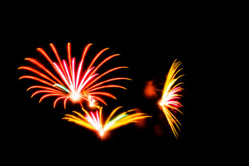 Fireworks with orange, pink and yellow colors light up the sky