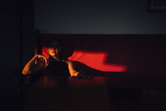 Woman sitting on the red couch lit with afternoon sun