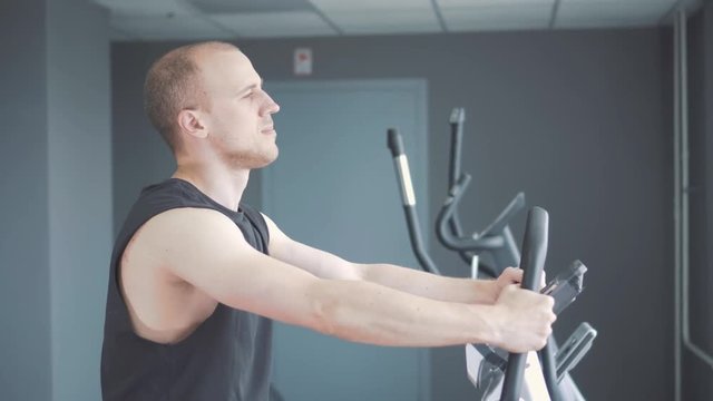 Young attractive man cycling on the exercise bike in the gym.