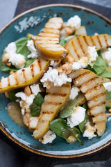 Close-up of salad with spinach leaves, grilled pears and feta cheese, selective focus