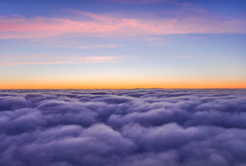 Stunning view above the clouds shortly after sunset seen from an airplane shortly before landing in Iceland. Tranquil scene with beautiful colors.
