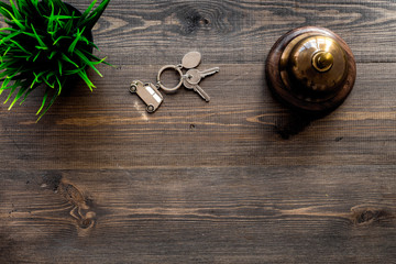 Hotel service bell and room keys on dark wooden table background top view copyspace