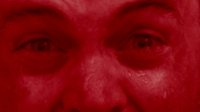 Close up of demonic man's face in red screaming and looking of pure evil.