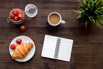 Light summer lunch. Coffee, strawberry, croissant on wooden background top view