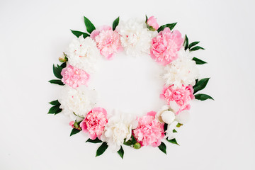 Frame wreath of pink peony flowers, branches, leaves and petals with space for text on white background. Flat lay, top view. Peony flower texture.