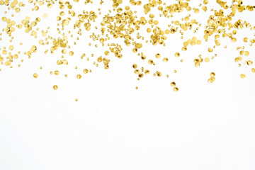 Golden confetti tinsel on white background. Flat lay, top view. Minimal background.