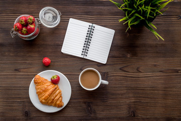Light summer lunch. Coffee, strawberry, croissant on wooden background top view copyspace
