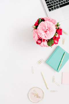 Flat lay home office desk. Female workspace with laptop, pink and red roses bouquet, golden accessories, mint diary on white background. Top view feminine background.