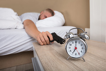 Man Holding Gun To Shoot Alarm Clock