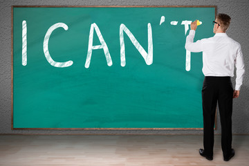 Businessman Rubbing Letter T From I Can't Written On Chalkboard