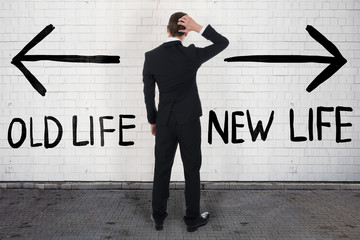 Confused Businessman Looking At Old And New Life On Wall