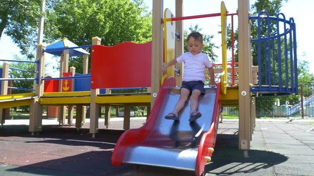 Child boy with great pleasure, rolling on a slide on the playground