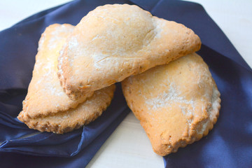 Beautiful festive composition: appetizing pastries on blue satin material on a white wooden background.Eating, dessert