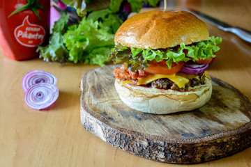 Hamburger with vegetables on wooden plate
