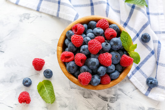 Raspberries and blueberries in a wooden bowl.