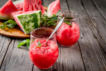 Summer fruit desserts, frozen cocktails. Ice cream granite from watermelon with mint, in portioned glasses, with slices of watermelon. On old rustic wooden table Copy space