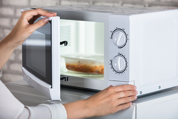 Woman's Hands Closing Microwave Oven Door And Preparing Food
