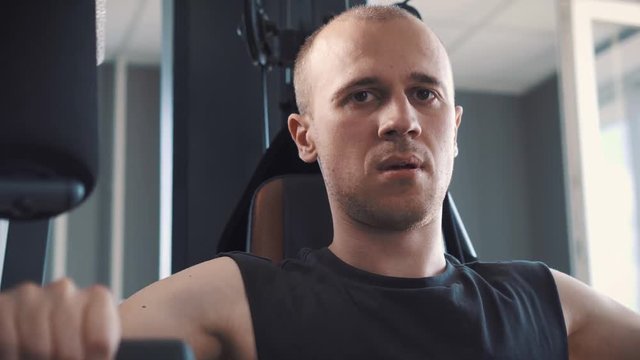 Young Muscular Man Training Hard On Rowing Machine In Fitness Studio.