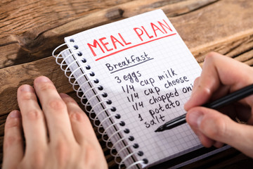 Person Making Meal Plan On Notebook