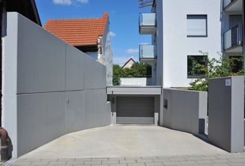 Moderne Einfahrt mit Beton-Wänden und Garage mit Automatik-Tor
