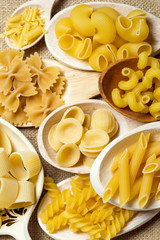 composition of raw Italian pasta in wooden spoons 