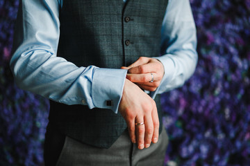 Close up image of a fashion the hands of a young businessman, handsome model man in casual cloth costume. Wearing the vest in the cage, black jeans and blue shirt.