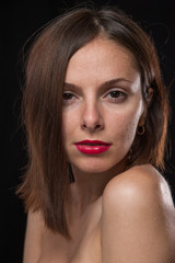 Unretouched, raw studio portrait of a young and pretty caucasian brunette girl with red lipstick, shot of black background with backlight. - 167409031