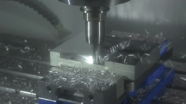 CNC machine smooths metal block, close up slow motion