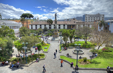 High view of the Independence Plaza in downtown Quito, with the independence monument, trees, gardens and people on a sunny morning. Quito, Pichincha, Ecuador.