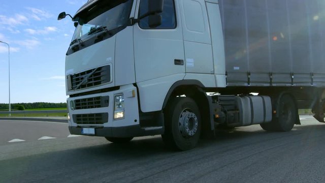 Speeding White Semi Truck with Cargo Trailer Turns on the Highway. Shot on RED EPIC-W 8K Helium Cinema Camera.