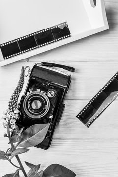 Old vintage camera, film and flower on wooden background. Black and white