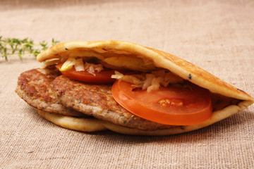 Burger in pita with onions and tomatoes on a fabric background