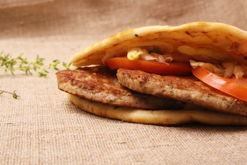 Burger in pita with onions and tomatoes on a fabric background