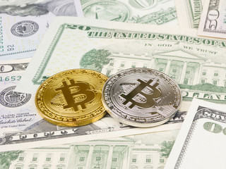 Golden and silver bitcoin coin on us dollars close up.