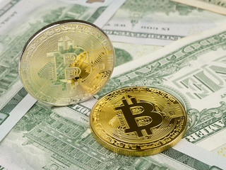 Golden and silver bitcoin coin on us dollars close up.