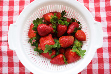 Close-up view of washed strawberries reflecting in a white pot