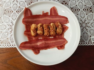 Close-up image of food fail - dry and wrinkled sausage decorated with bacon strips