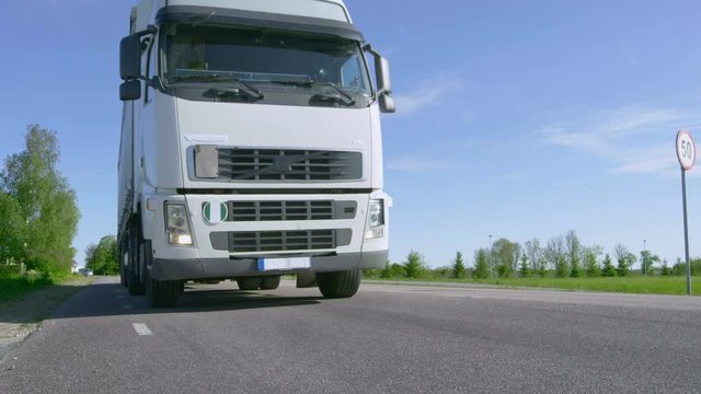 Eighteen Wheeler Semi Truck Drives On the Empty Country Road Passes Camera, Wheels Spinning. Shot on RED EPIC-W 8K Helium Cinema Camera.