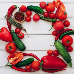 Red pepper, condiment, zucchini, cucumber, tomatoes and green chilies on a white wooden background.