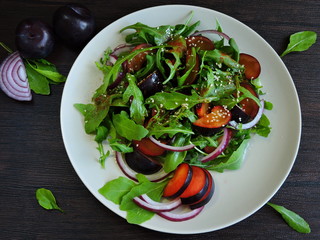 Fitness salad with arugula and plums on a plate. Top view.