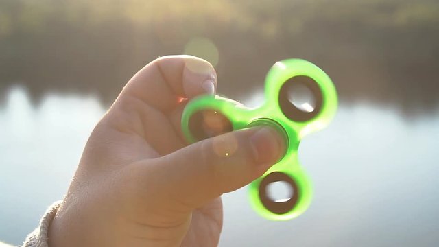 Young man playing with fidget spinner, slow motion.