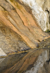 Fototapeta premium Reflection of natural rock, dyed with mineral, in a hot spring pool