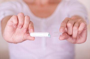 Close up of a young woman pointing in front of her a menstruation cotton tampon in a blurred background