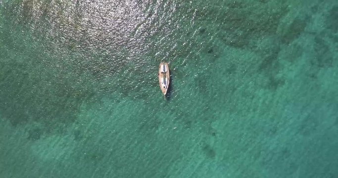 Aerial, a lonely saling ship in a beautiful bay with crystalline water