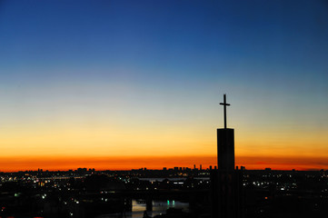 Naklejka premium cross on church tower in front of sunset sky