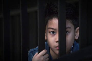 asian boy Hand in jail looking out the window