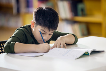 Happy asian child doing homework with smile face.